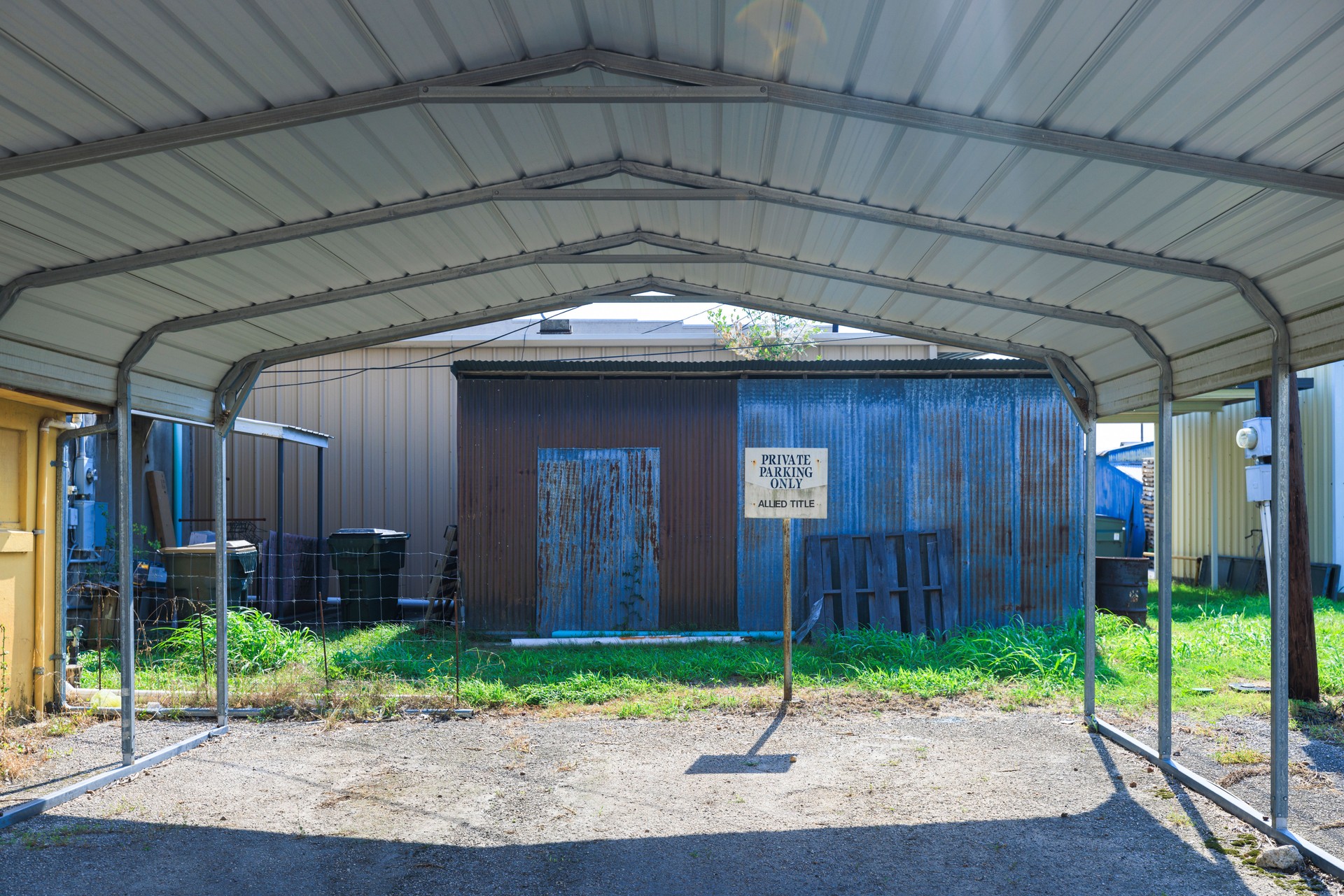 Sheltering vehicles under metal canopy in small American town. Rustic carport provides private parking in Hallettsville, Texas